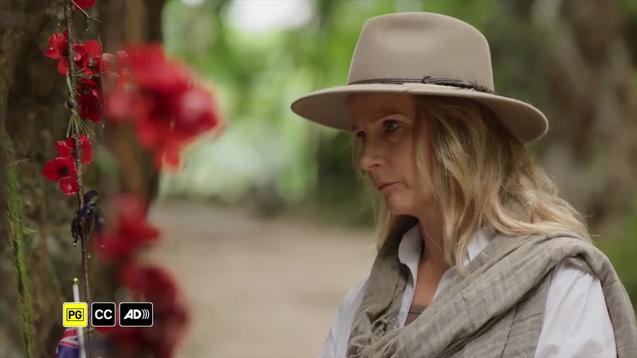 A woman in a hat, draped in a scarf, looks thoughtfully towards a display of red poppies. The scene feels like it's from an ABC Australia production, likely ...