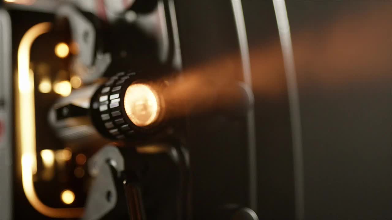 A bright, warm light bursts from the projector's lens, casting a soft glow. The beam of light extends outward, illuminating the surrounding area.