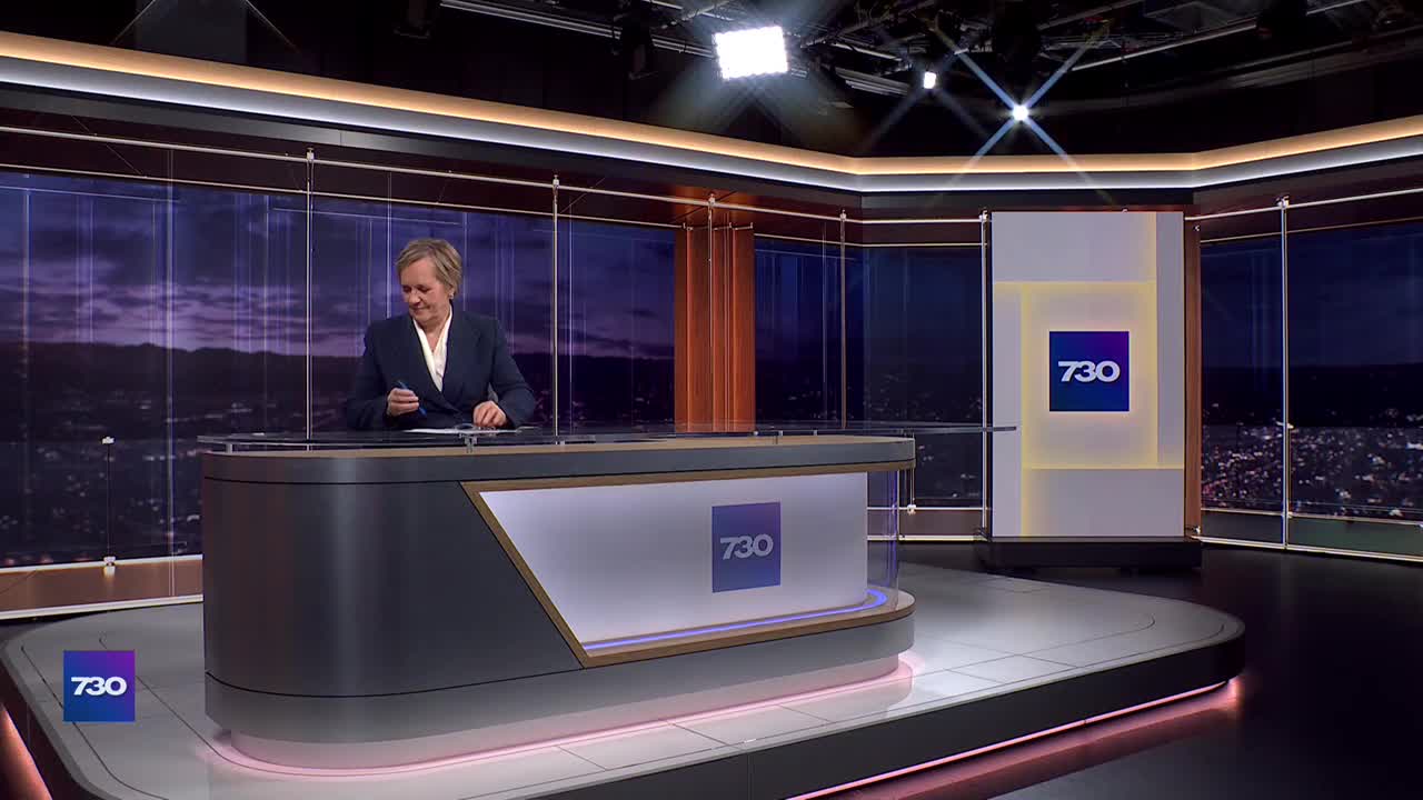 The presenter at the ABC Australia news desk is poised, pen in hand, looking down at her notes. The "7.30" logo is prominent on the desk and backdrop.