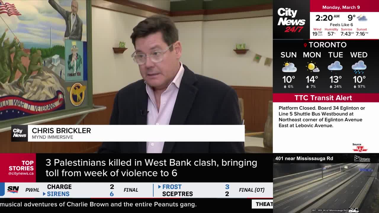 A man in a suit and light pink shirt speaks on camera, with a mural depicting World War II veterans behind him. A CityNews Toronto graphic displays the date ...