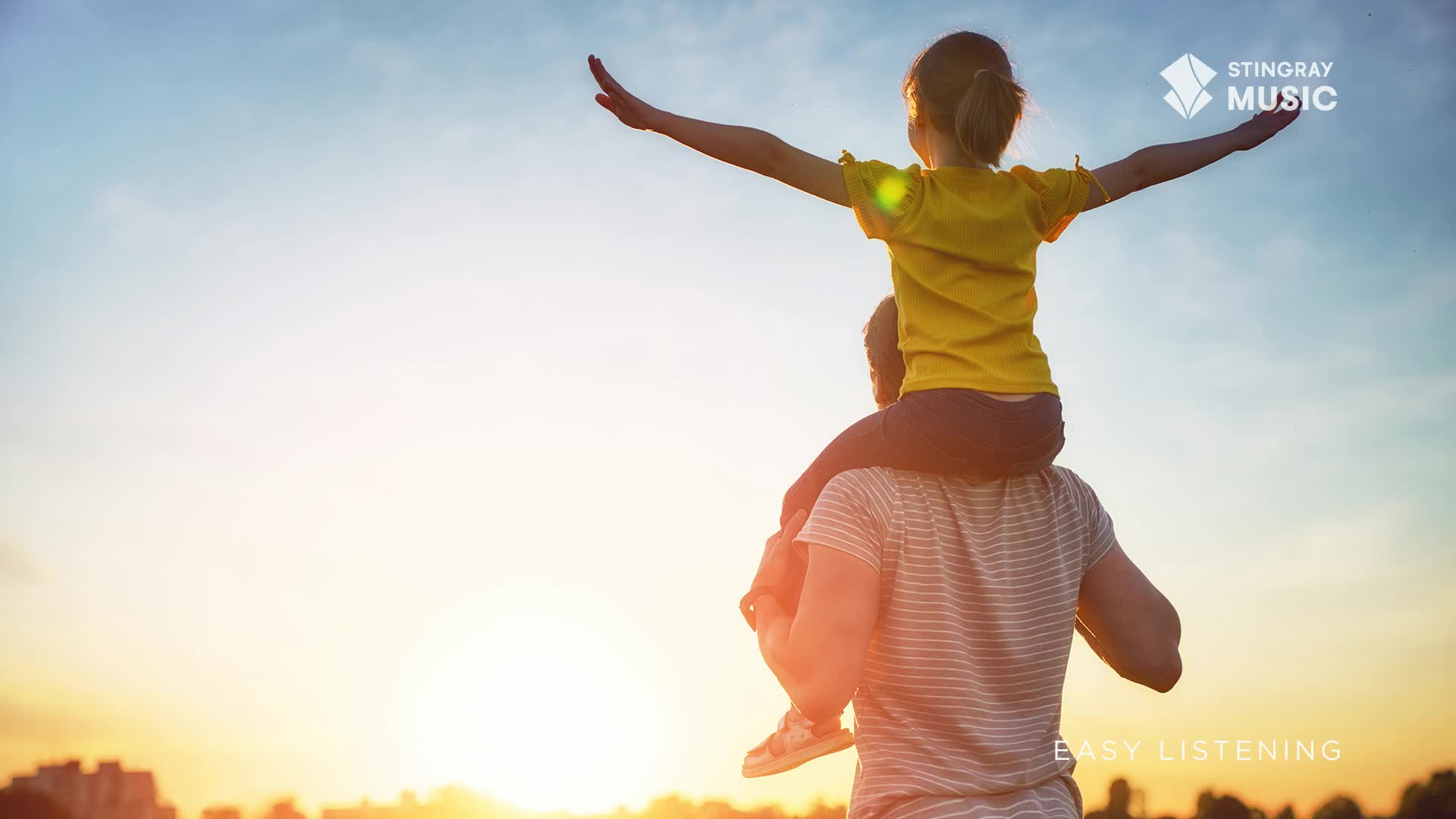 A child, perched on someone's shoulders, stretches their arms toward the sky. The warm light of the setting sun bathes them, a perfect backdrop for Stingray ...