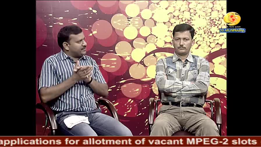 On a DD Arun Prabha set, a man in a striped shirt gestures with his hands while speaking. Across from him, a man in a plaid shirt sits with his arms crossed,...
