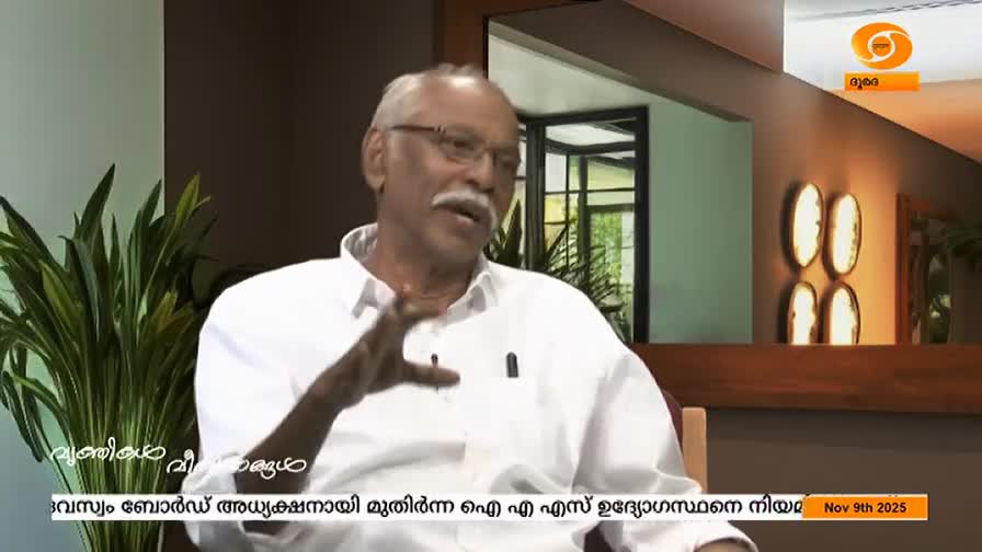 A man with a white mustache and glasses gestures with his hands while speaking. The DD Malayalam logo and text are visible at the bottom of the screen.