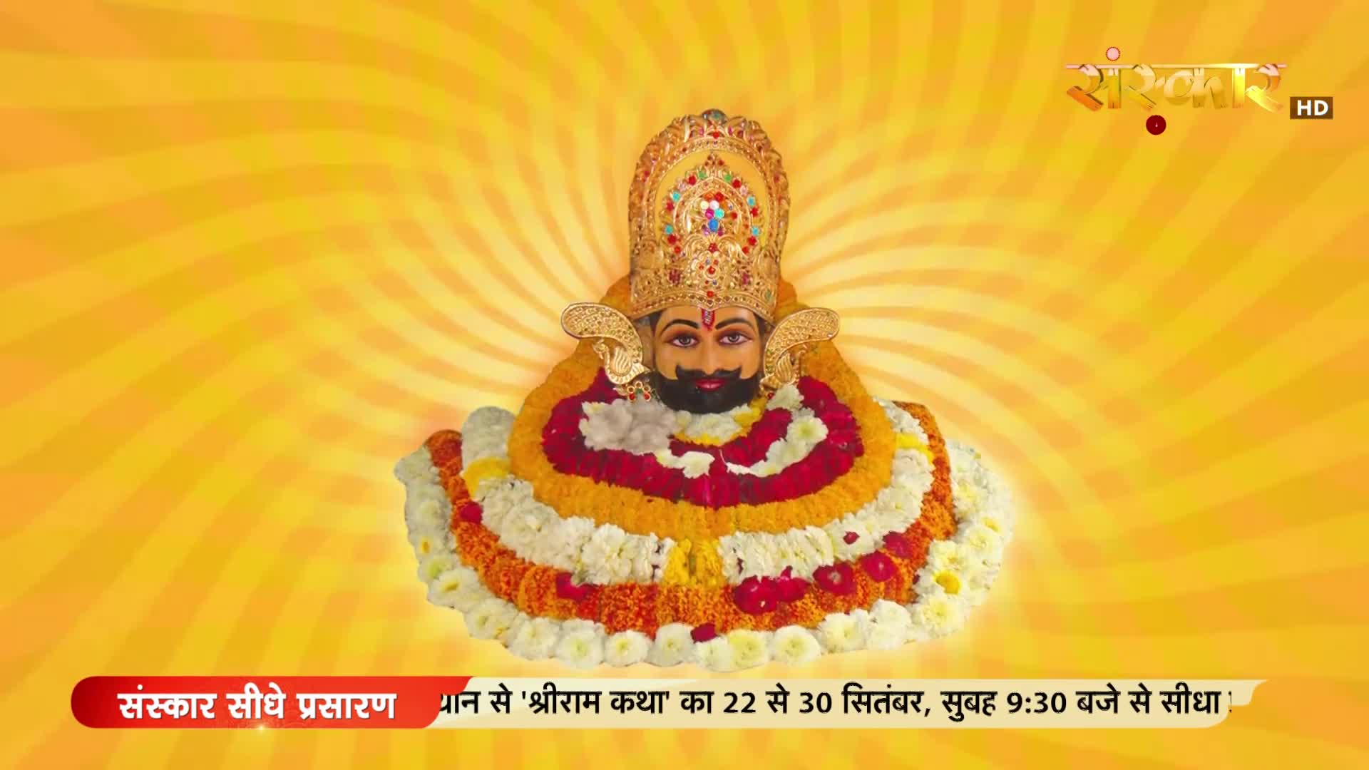 A deity is centered, adorned with a jeweled crown and garlands of flowers. The Sanskar TV logo and text about "Shriram Katha" broadcast details are at the to...