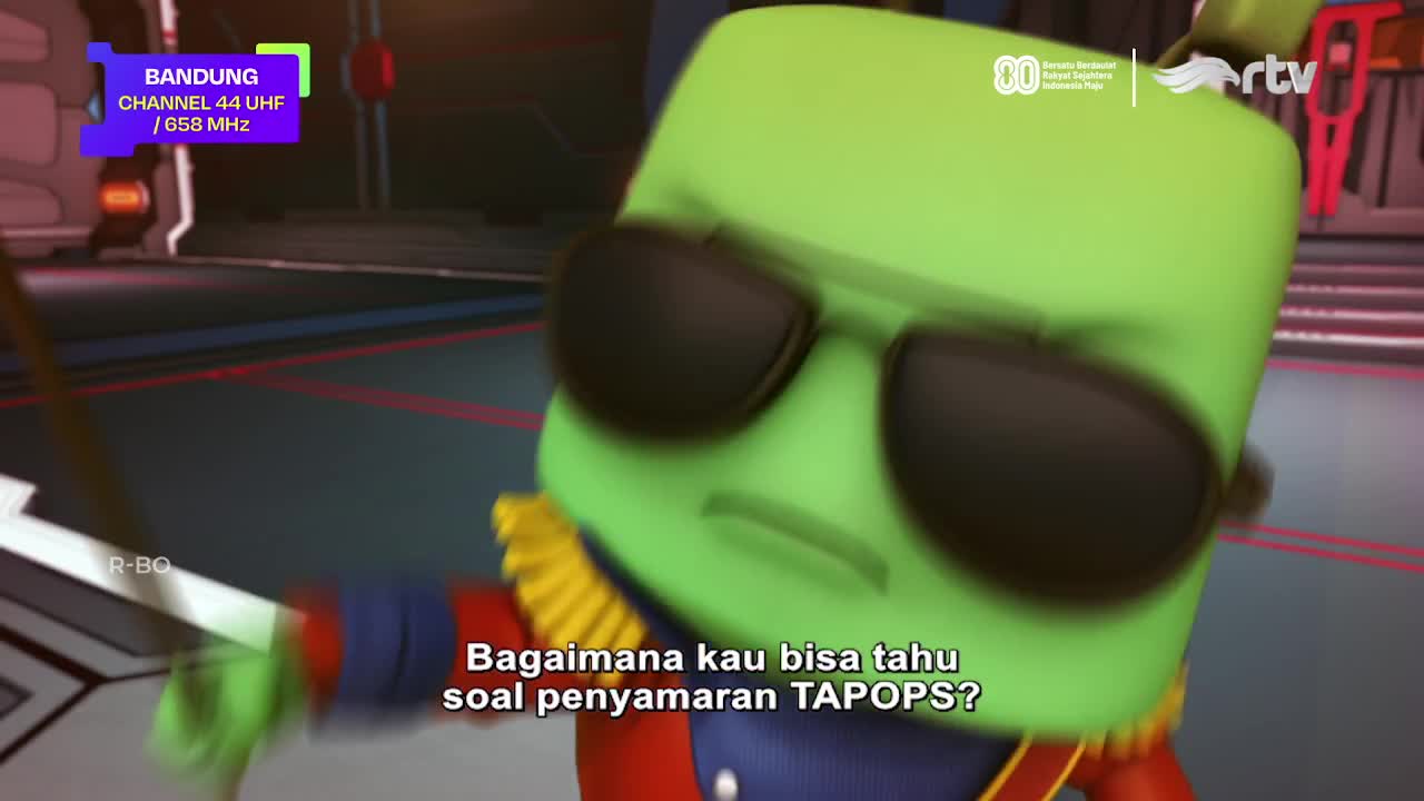 A green, square-headed character wearing sunglasses is in motion, its face slightly blurred. Indonesian text, along with the Rajawali TV logo, appears on scr...