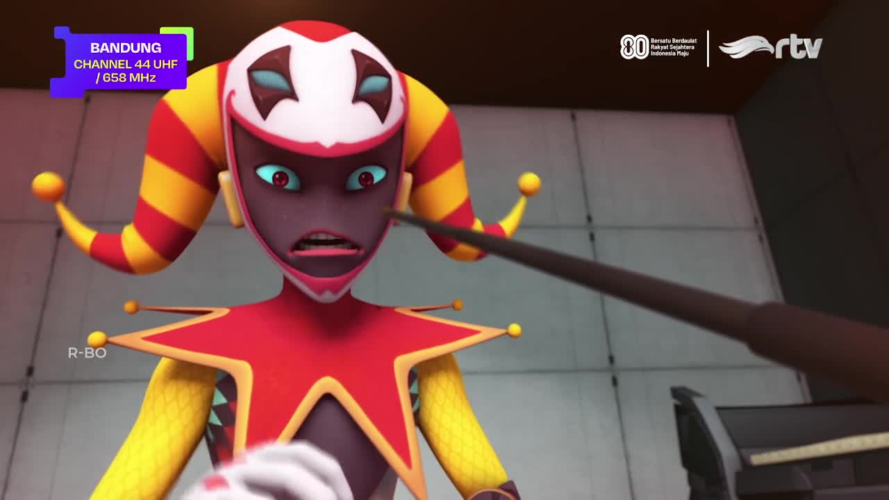 A cartoon jester, with a startled expression, is being poked by a dark, thin object. The scene is from Rajawali TV in Bandung, Indonesia, as indicated by the...