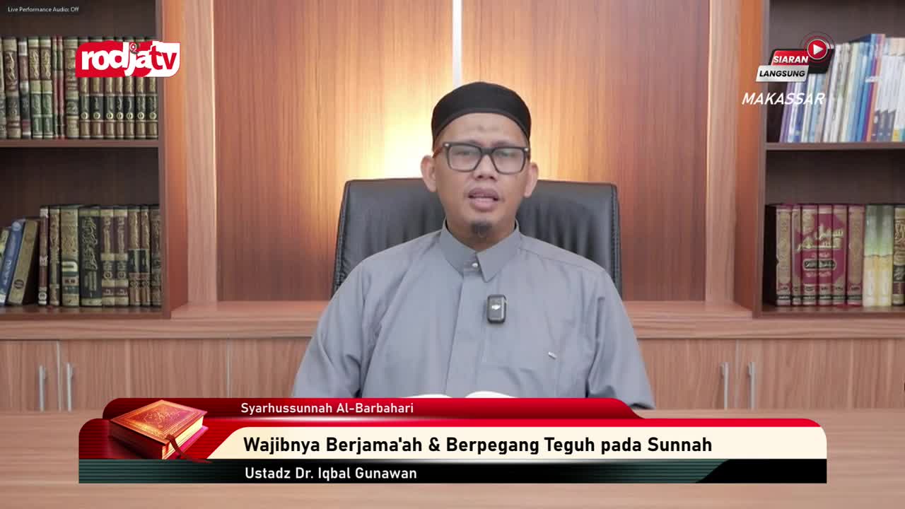 A man in a black cap and glasses speaks directly to the camera, his hands gesturing slightly. The Rodja TV logo is visible, and a banner below him displays t...