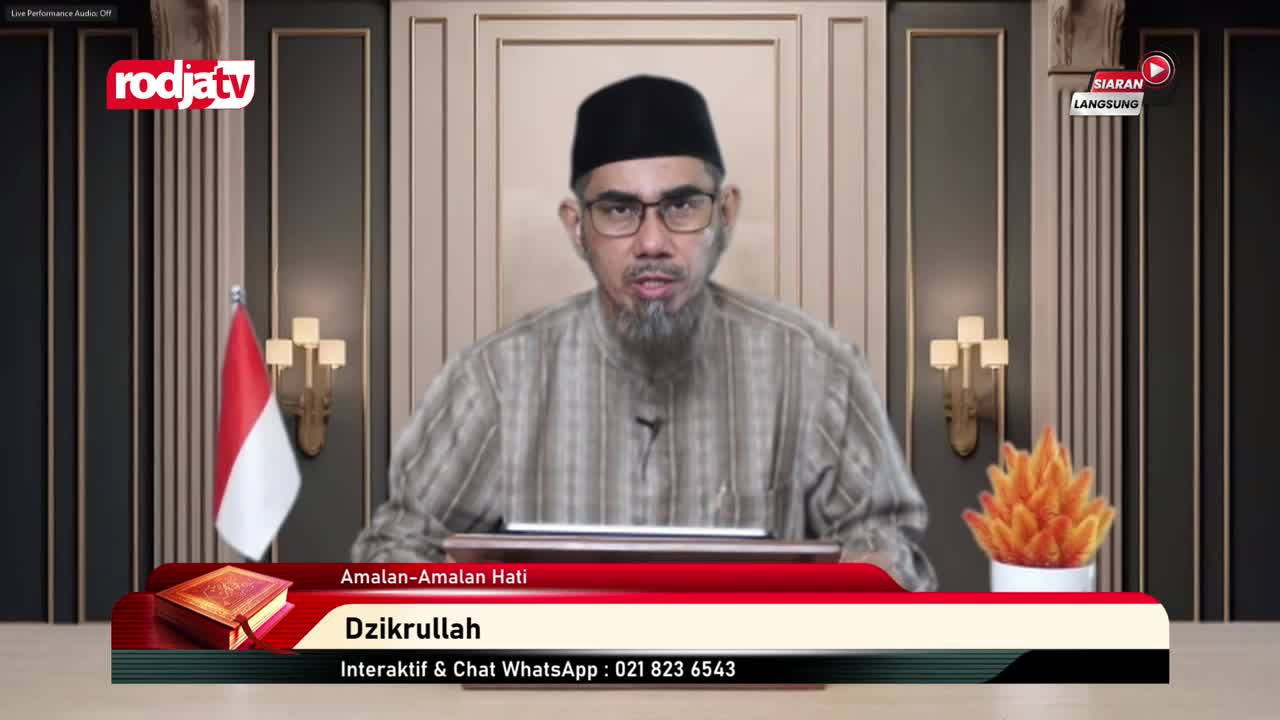 A man with a beard and glasses speaks directly into the camera from a Rodja TV studio. Behind him, the Indonesian flag and a decorative light fixture flank a...