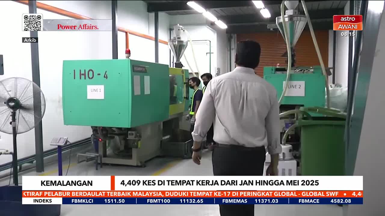 A man in a white shirt walks past large green machines, labeled "Line 1" and "Line 2." The Astro Awani logo is visible in the corner, and a news ticker at th...