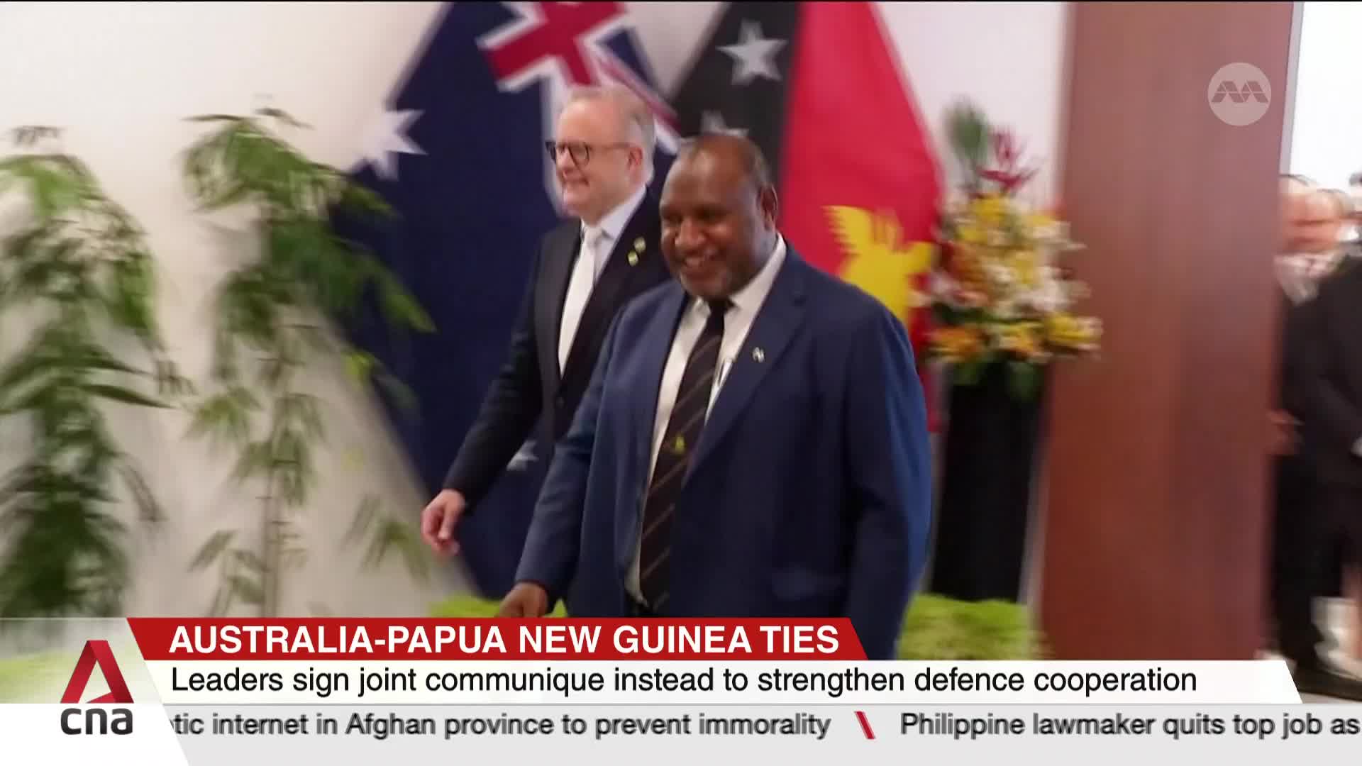 Two men in suits are walking towards the camera, smiling. Behind them, the flags of Australia and Papua New Guinea are visible, as reported by CNA Internatio...