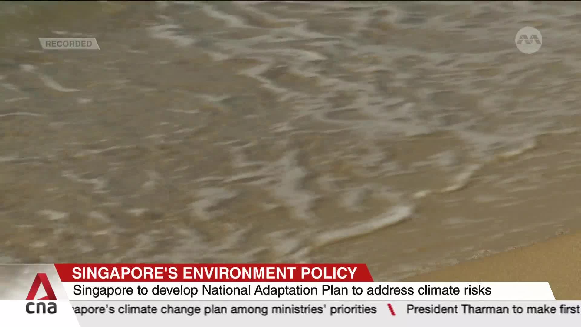 Gentle waves lap at the sandy shore, the water a mix of white foam and light brown. The CNA International graphic at the bottom highlights Singapore's climat...