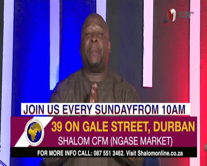 A man in a brown shirt clasps his hands, eyes closed, as the camera focuses on him. Below, a banner on 1KZN TV invites viewers to a service in Durban.