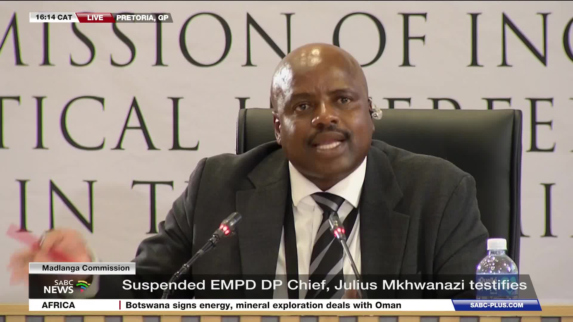 A man in a suit and tie speaks into a microphone, his hand gesturing slightly. The SABC News banner at the bottom of the screen identifies him as Julius Mkhw...