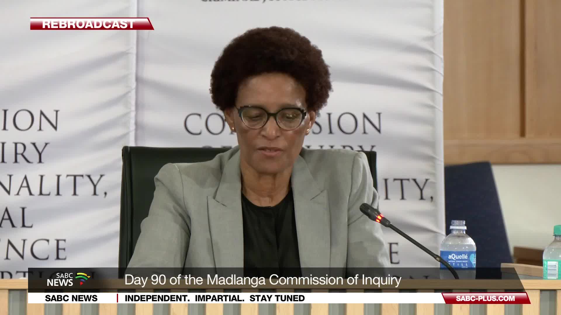 A woman in a grey blazer speaks into a microphone at the Madlanga Commission of Inquiry. The SABC News banner indicates this is Day 90 of the proceedings.