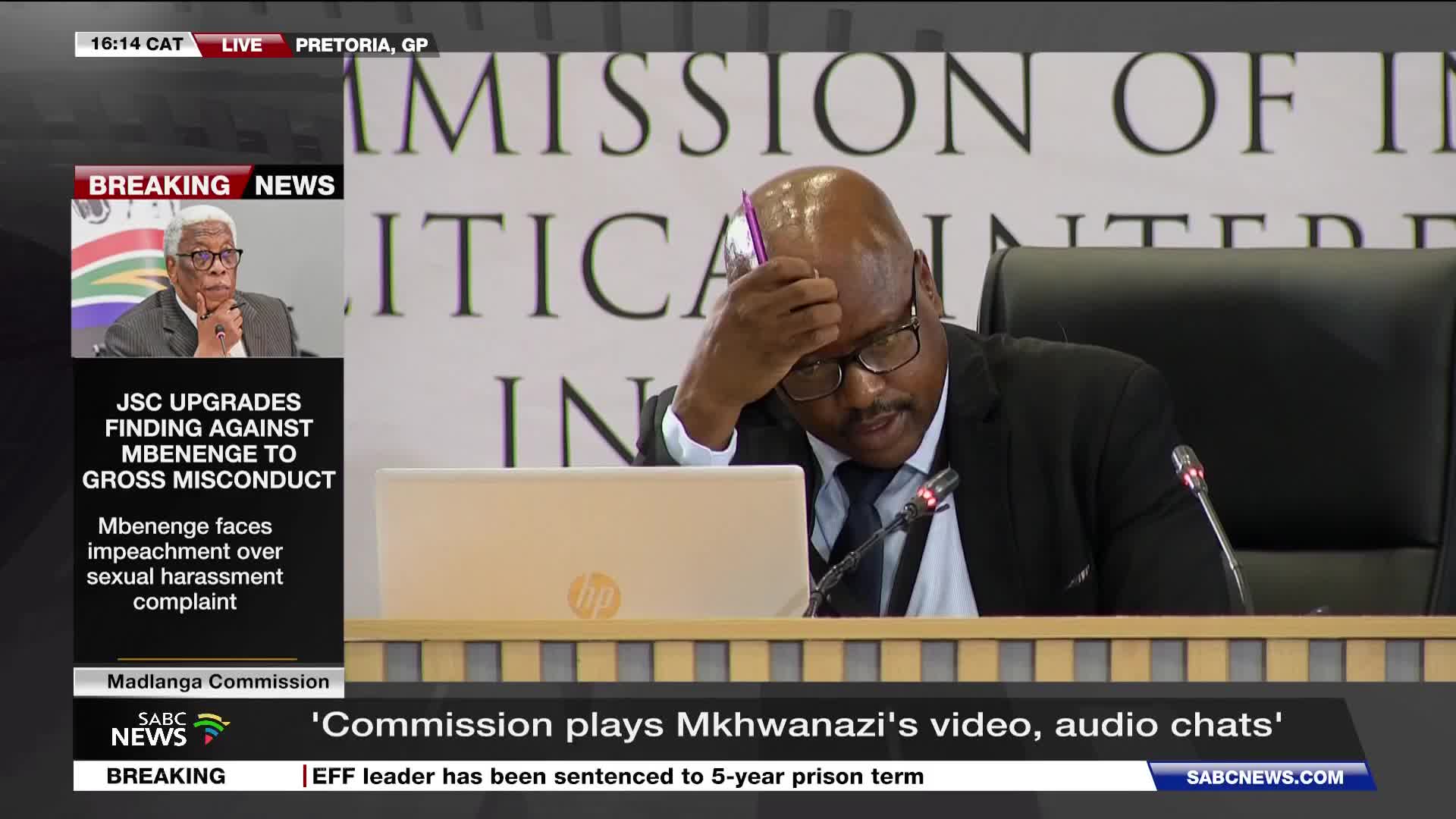A man in a suit leans forward, his hand on his forehead, a pink pen clutched in his fingers. The SABC News chyron announces "Commission plays Mkhwanazi's vid...