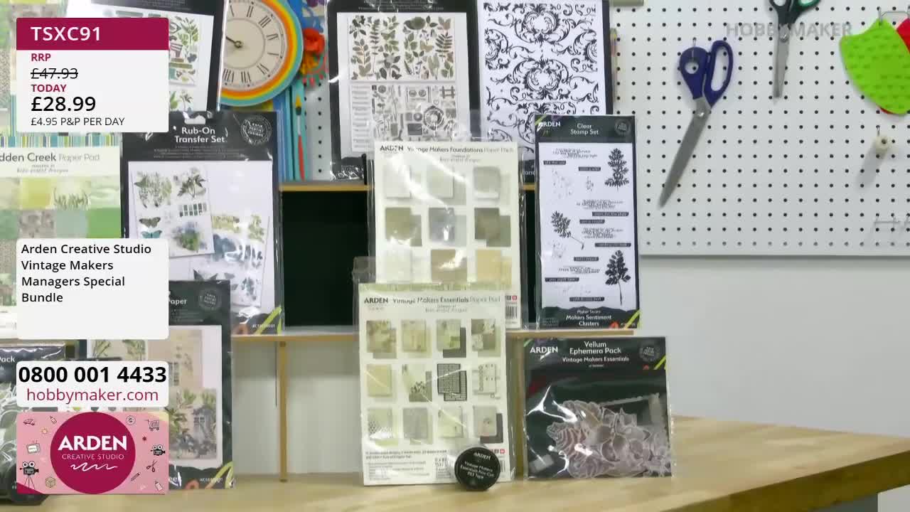 A display of craft supplies, including rub-on transfers and patterned paper, is laid out on a table. A pegboard behind the table holds scissors and other cra...
