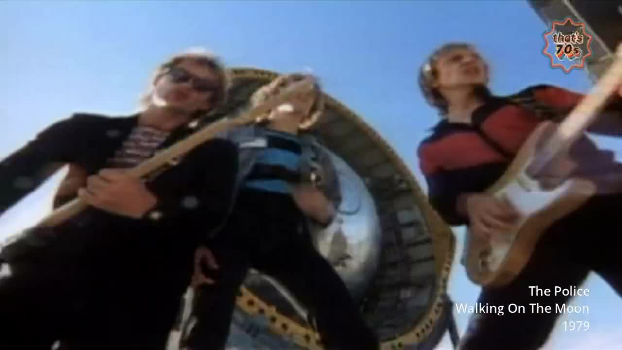 Three blokes are playing guitars, silhouetted against a bright sky. The middle one wears a blue and black striped shirt, while the one on the right has a red...