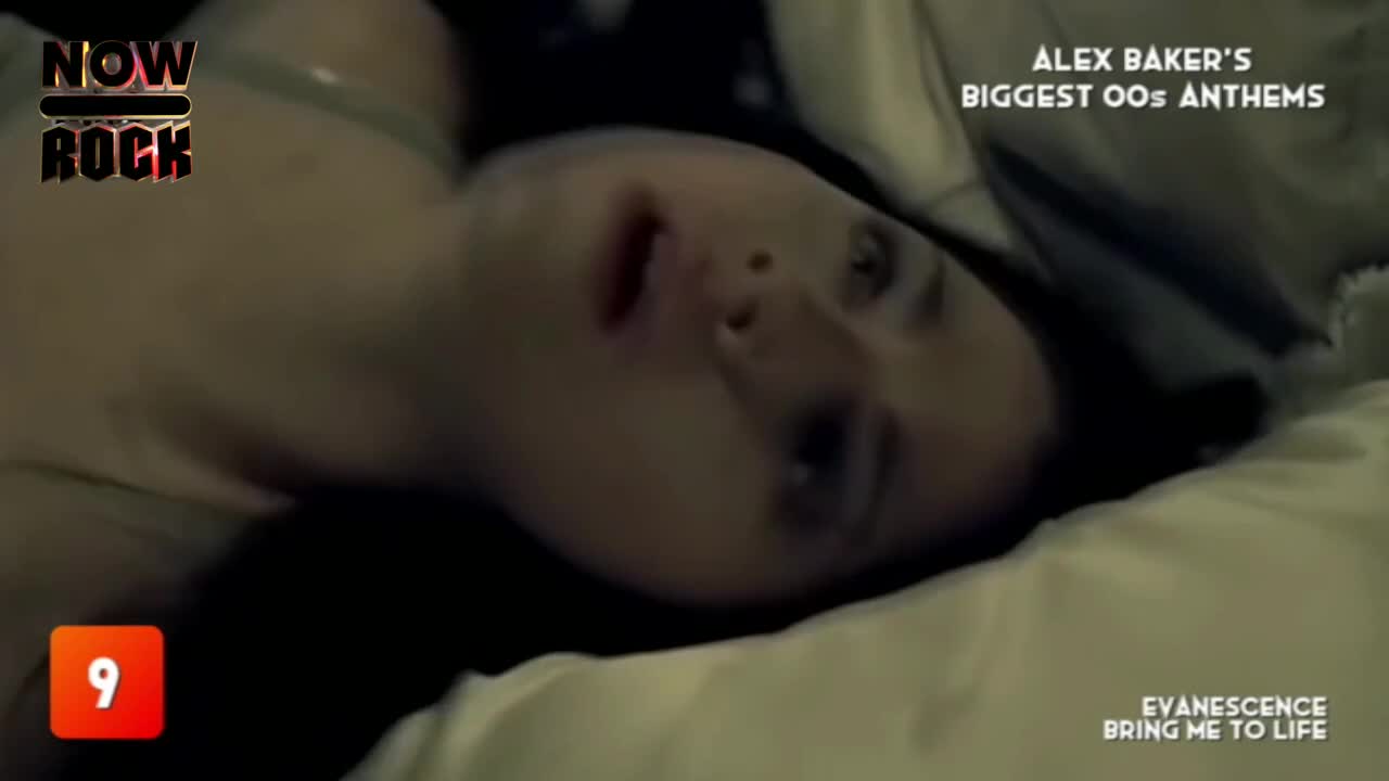The woman lies on a bed, eyes open and looking upwards.  "Bring Me to Life" by Evanescence is playing on NOW Rock, with the song's title appearing on the scr...