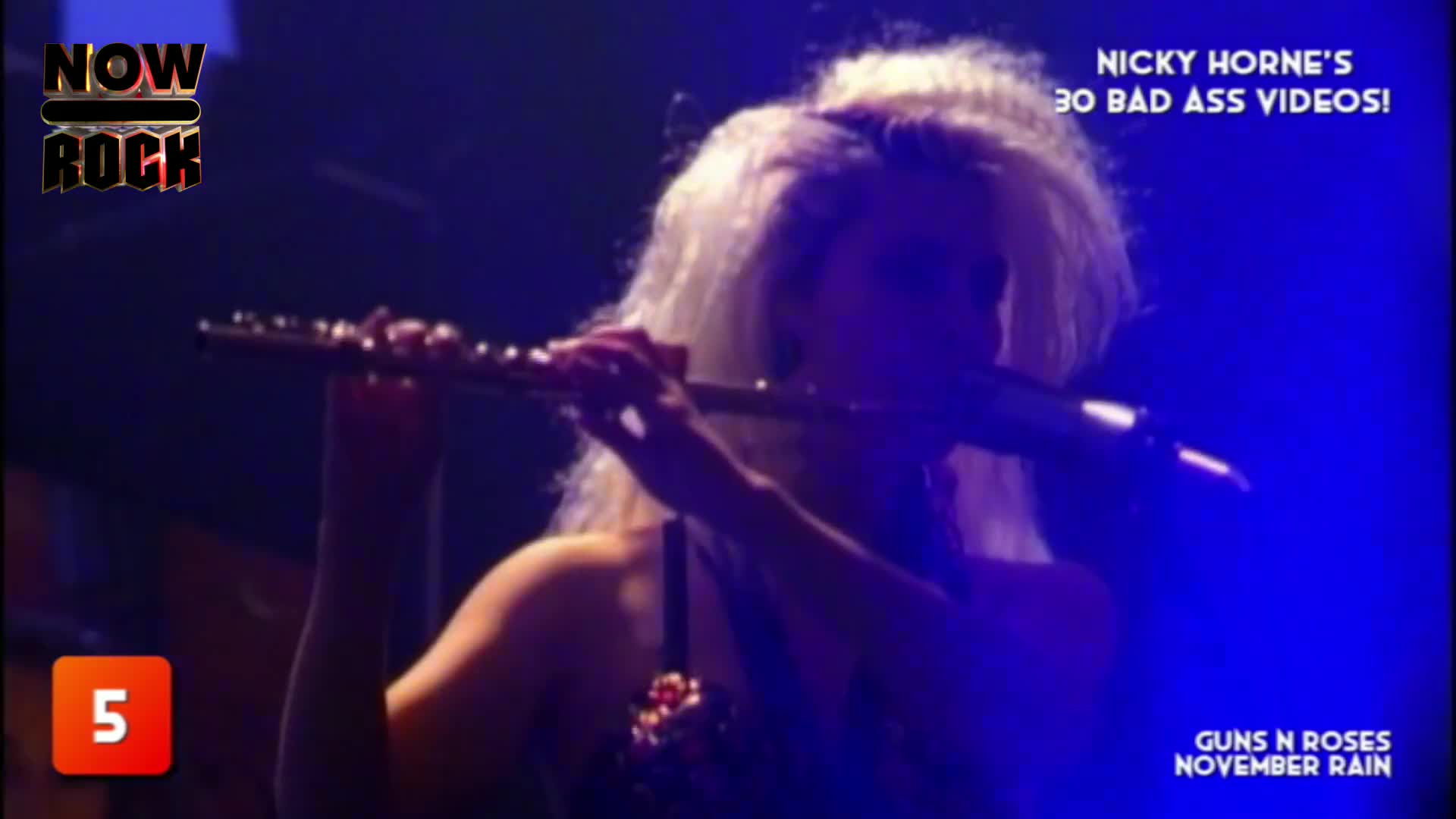 A woman with bright blonde hair holds a flute, her face partially obscured by the instrument and the stage lighting. The NOW Rock logo and a countdown number...