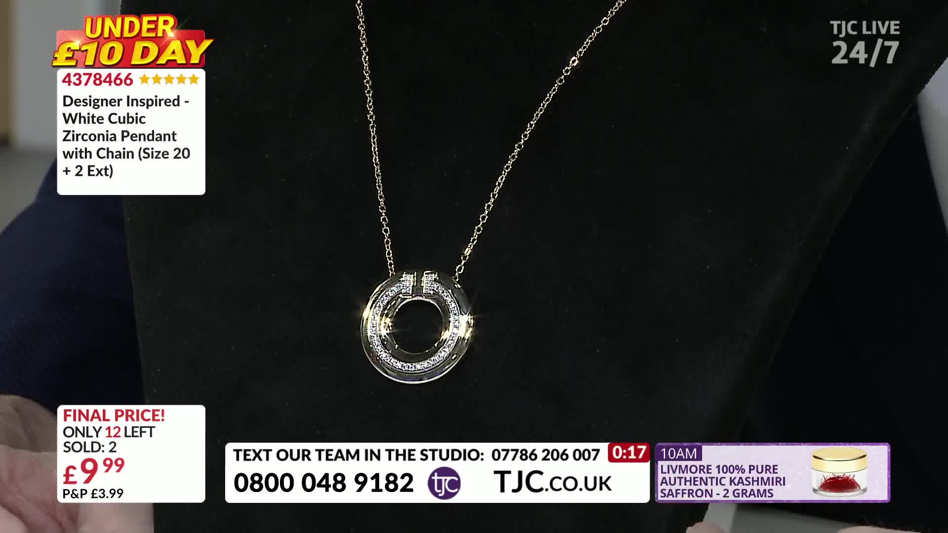 A pendant necklace with a silver chain hangs against a black backdrop. The circular pendant is encrusted with small, sparkling stones.