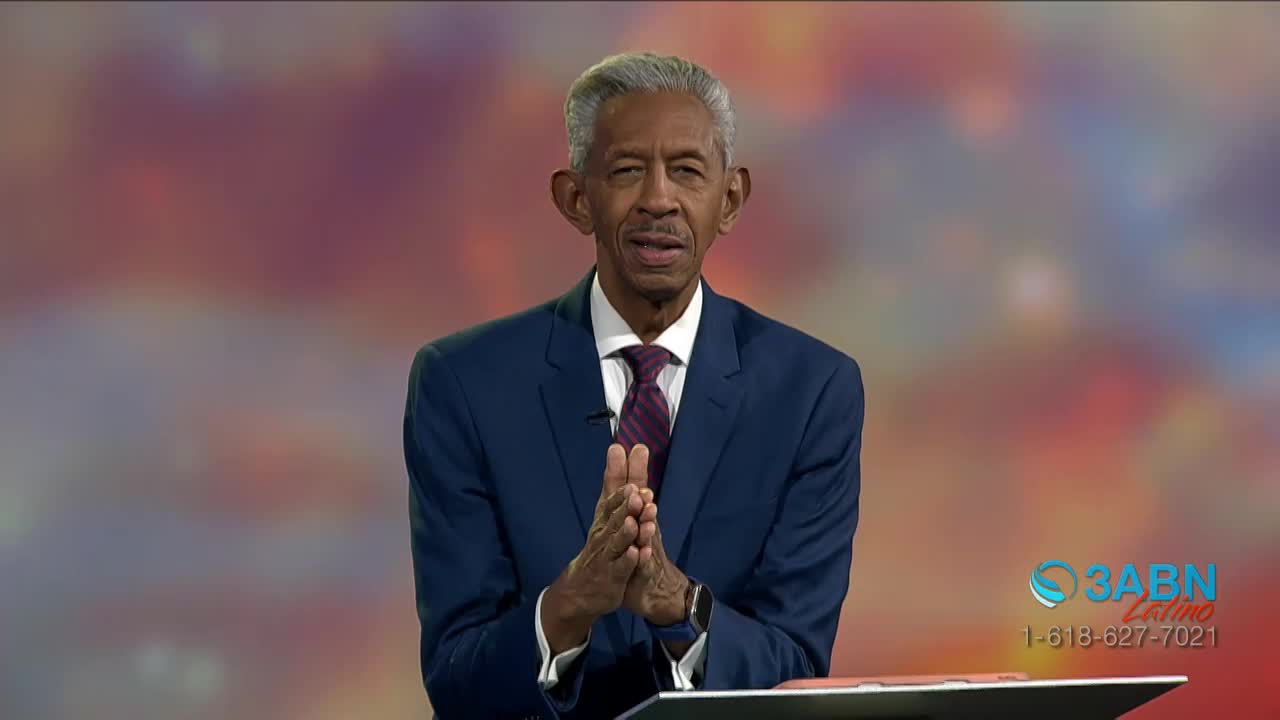 A man in a blue suit stands before a colorful backdrop, his hands clasped together. The 3ABN Latino logo is visible in the corner, with a phone number listed...