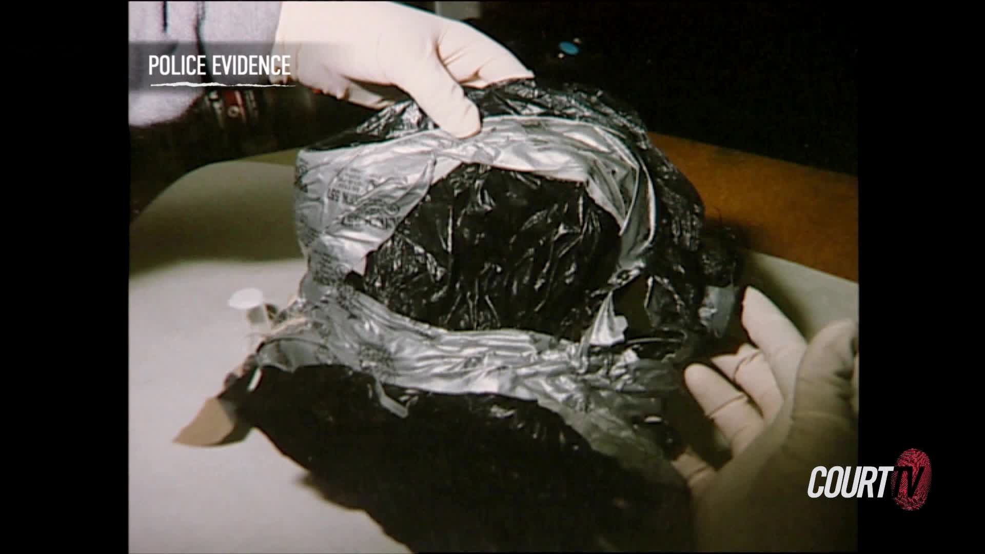 Gloved hands are carefully pulling open a black plastic bag, revealing a dark, crumpled interior. The scene is labeled "Police Evidence" on the Court TV broa...