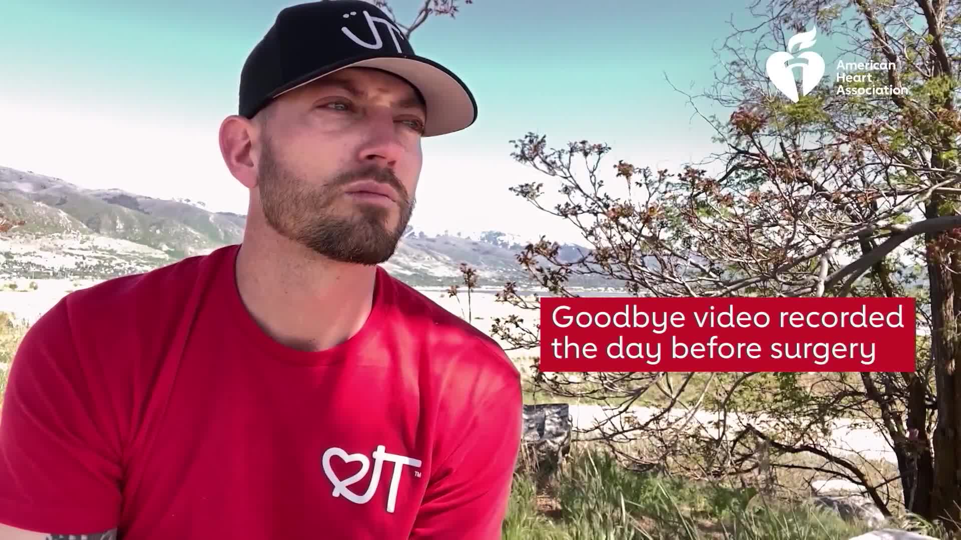 A man in a red shirt and a black cap looks off-camera, the text "Goodbye video recorded the day before surgery" appears on the screen. The scene is set outdo...