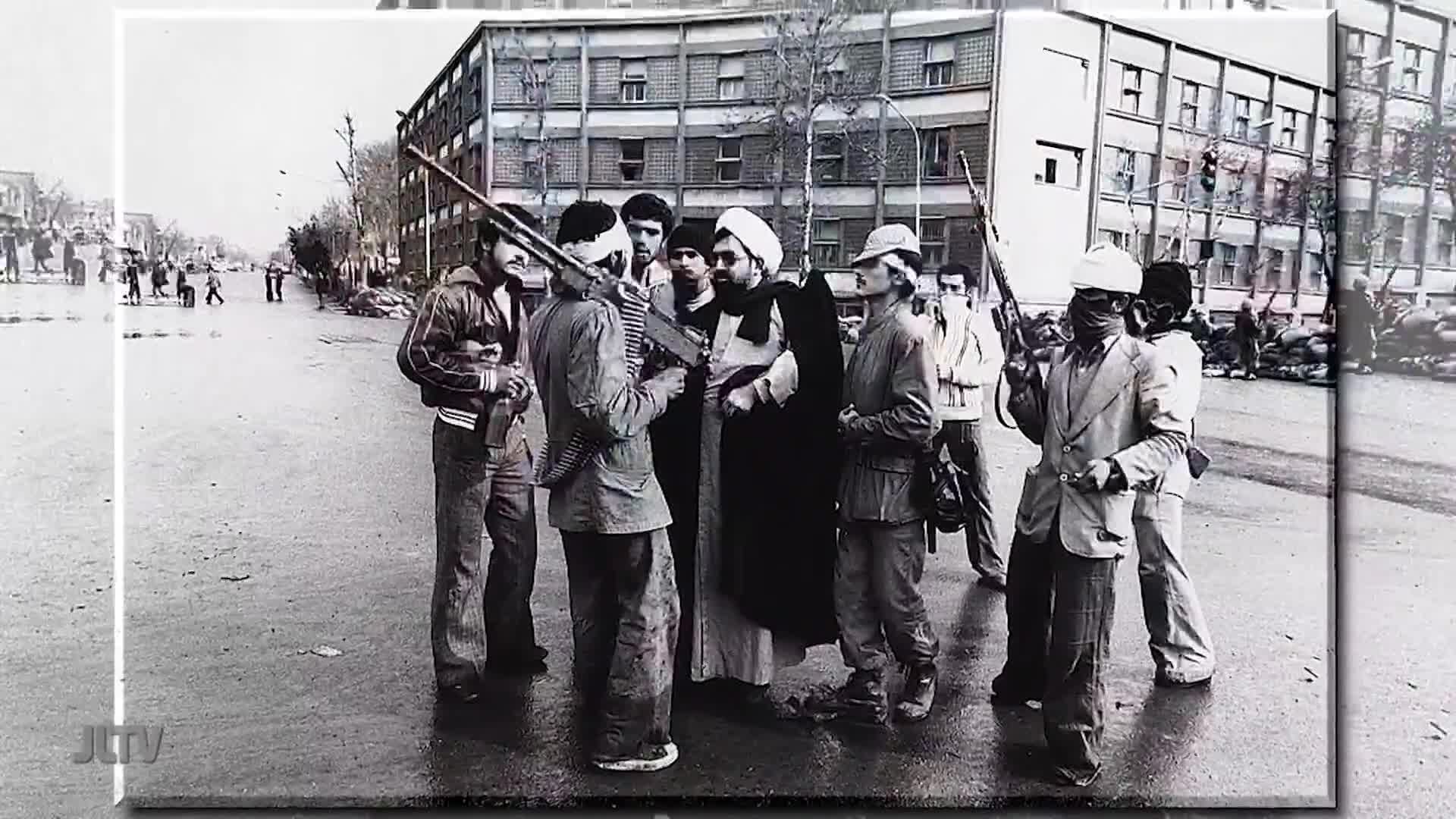 A group of men, some with rifles, surround a robed figure in the middle of a street. The scene, broadcast by United States Jewish Life Television, shows a te...