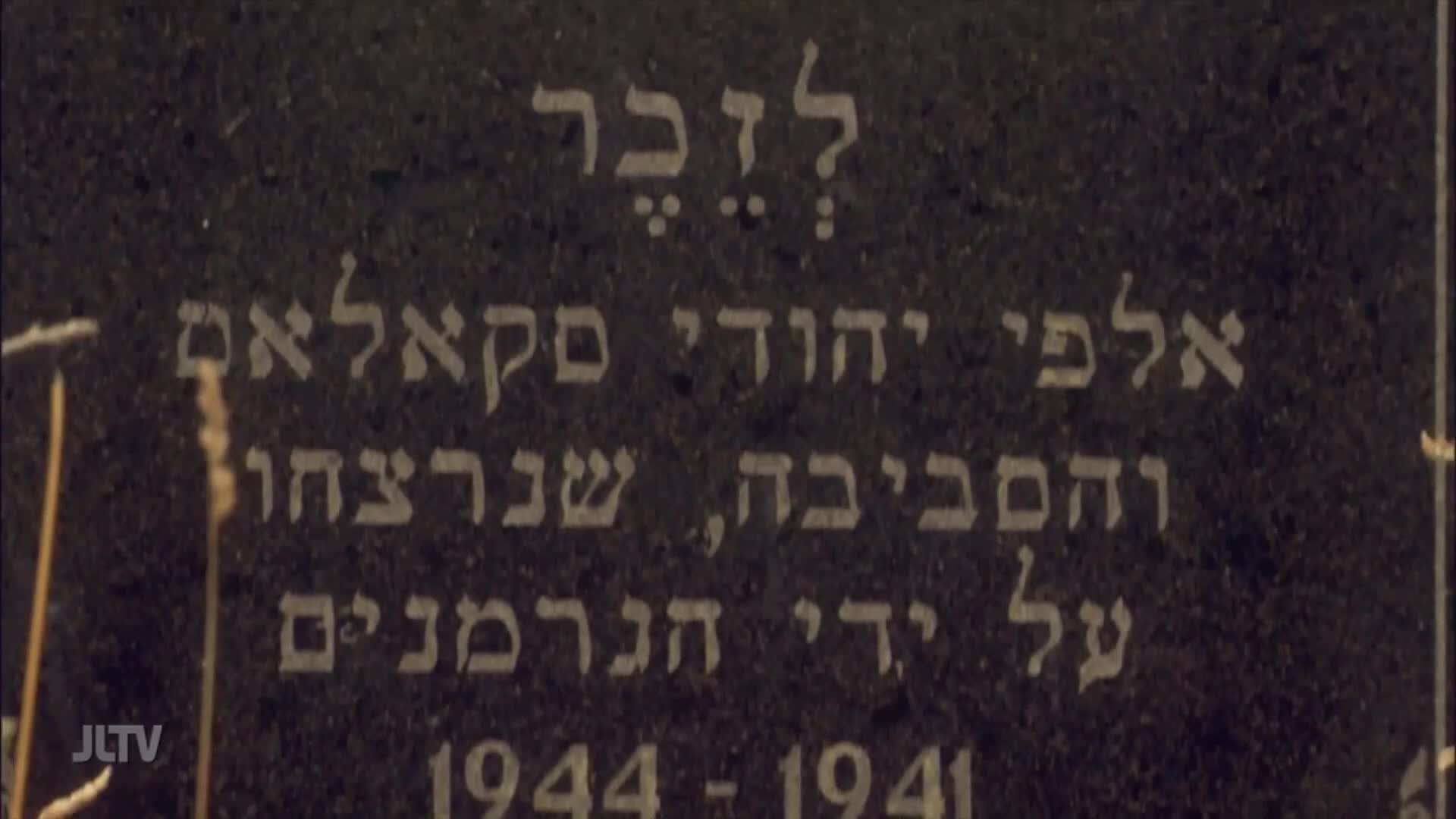 On a dark stone, Hebrew letters are etched, commemorating those murdered by the Nazis. The JLTv logo is visible in the corner, likely from a documentary film...