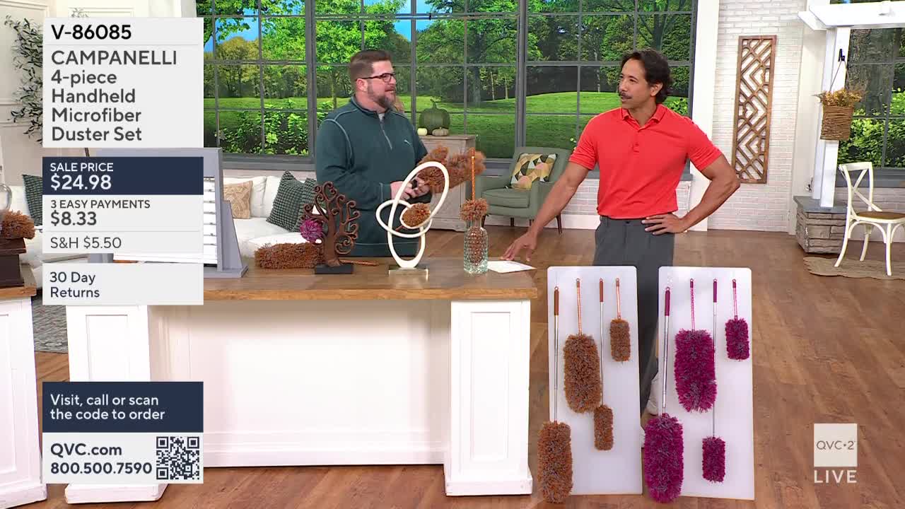 Two men stand behind a table on QVC2, one holding a brown duster and the other gesturing toward a display of the same product. The camera focuses on the dust...