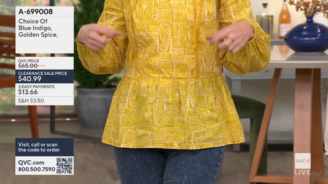 A woman on QVC2, in the United States, gestures toward the yellow patterned top she's wearing. The clearance sale price of $40.99 is displayed on the screen.