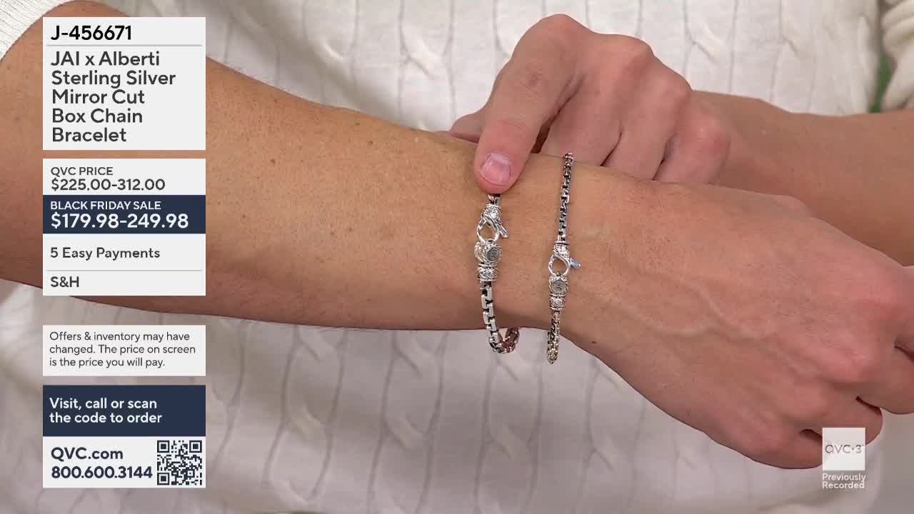 A hand holds two silver bracelets side-by-side, showcasing the jewelry. The bracelets, with intricate clasps, are displayed against the backdrop of a white s...