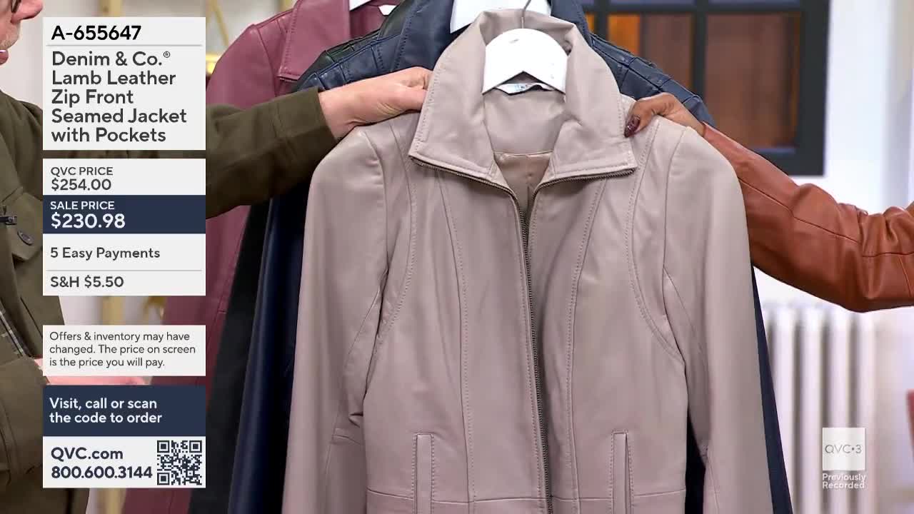 A woman holds up a light beige leather jacket, showing off the zip front and pockets. Other colored jackets hang behind it, and the price is displayed on the...