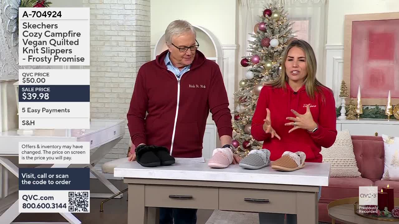 A woman in a red sweatshirt gestures towards the various colors of Skechers slippers displayed on a table. The man next to her, wearing a burgundy zip-up, gl...