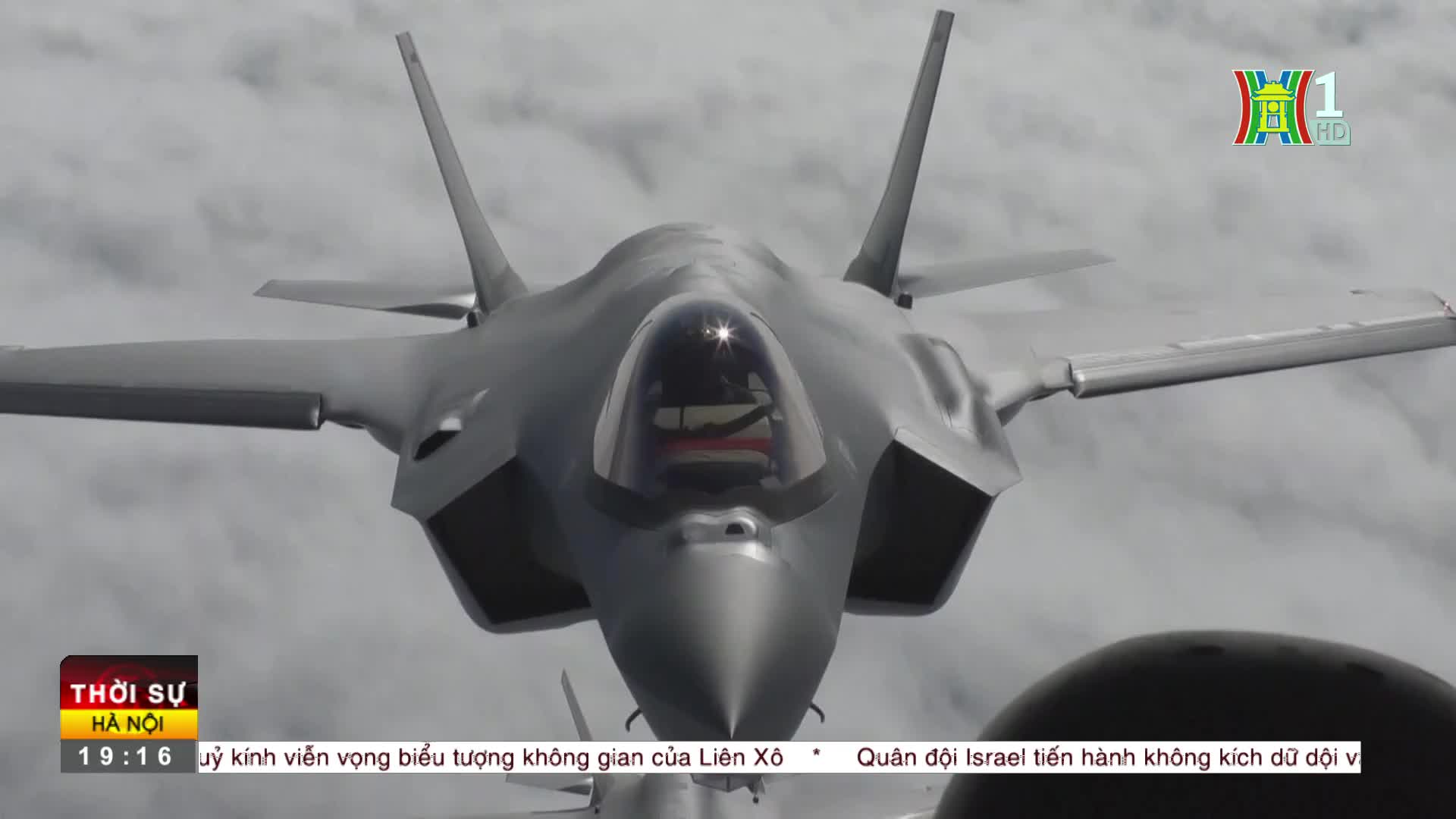 A gray jet, its nose pointed directly at me, cuts through the overcast sky. The HanoiTV1 logo and Vietnamese text are visible in the lower corners of the scr...